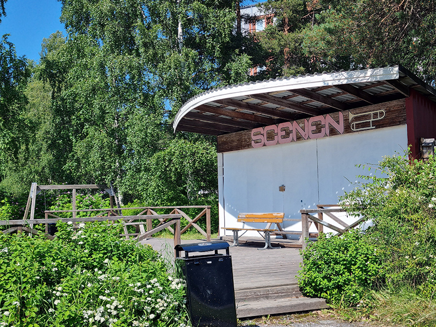 En mindre scen med ett trädäck framför finns mitt i parken