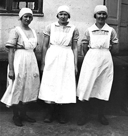 Tre kvinnor med vita förkläden.