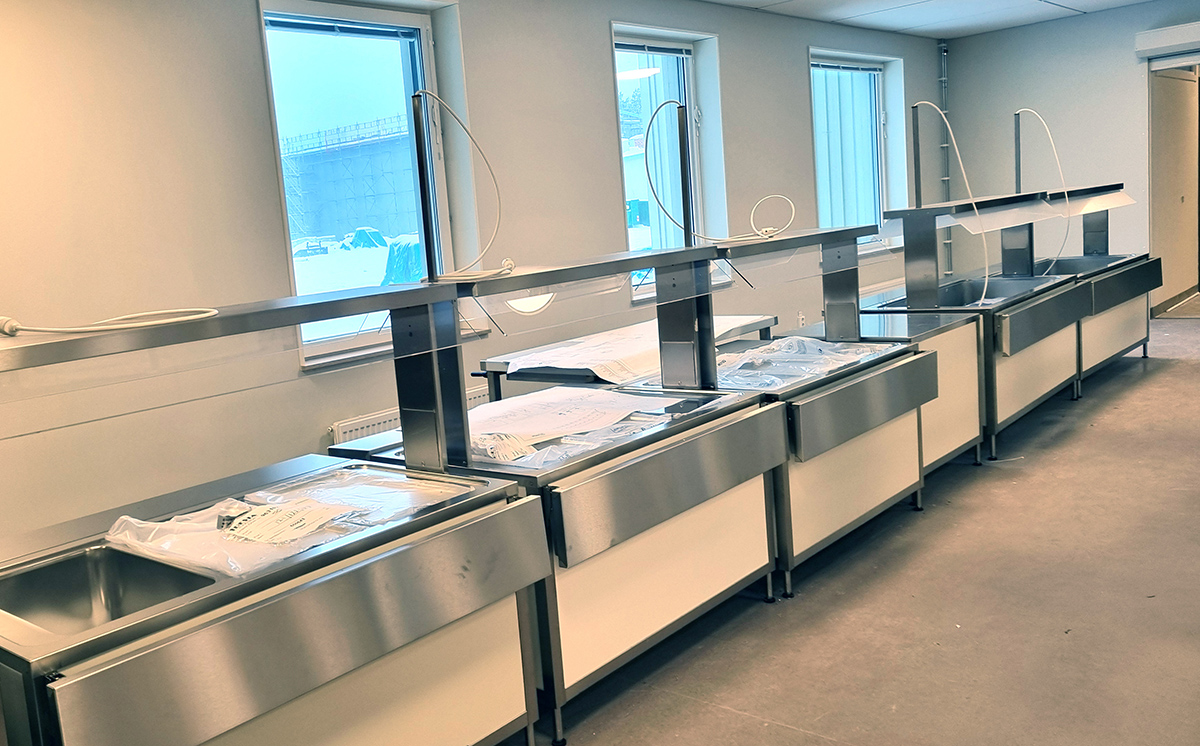 Bild på serveringskärl för maten som står i i lång rad med fönster bakom.