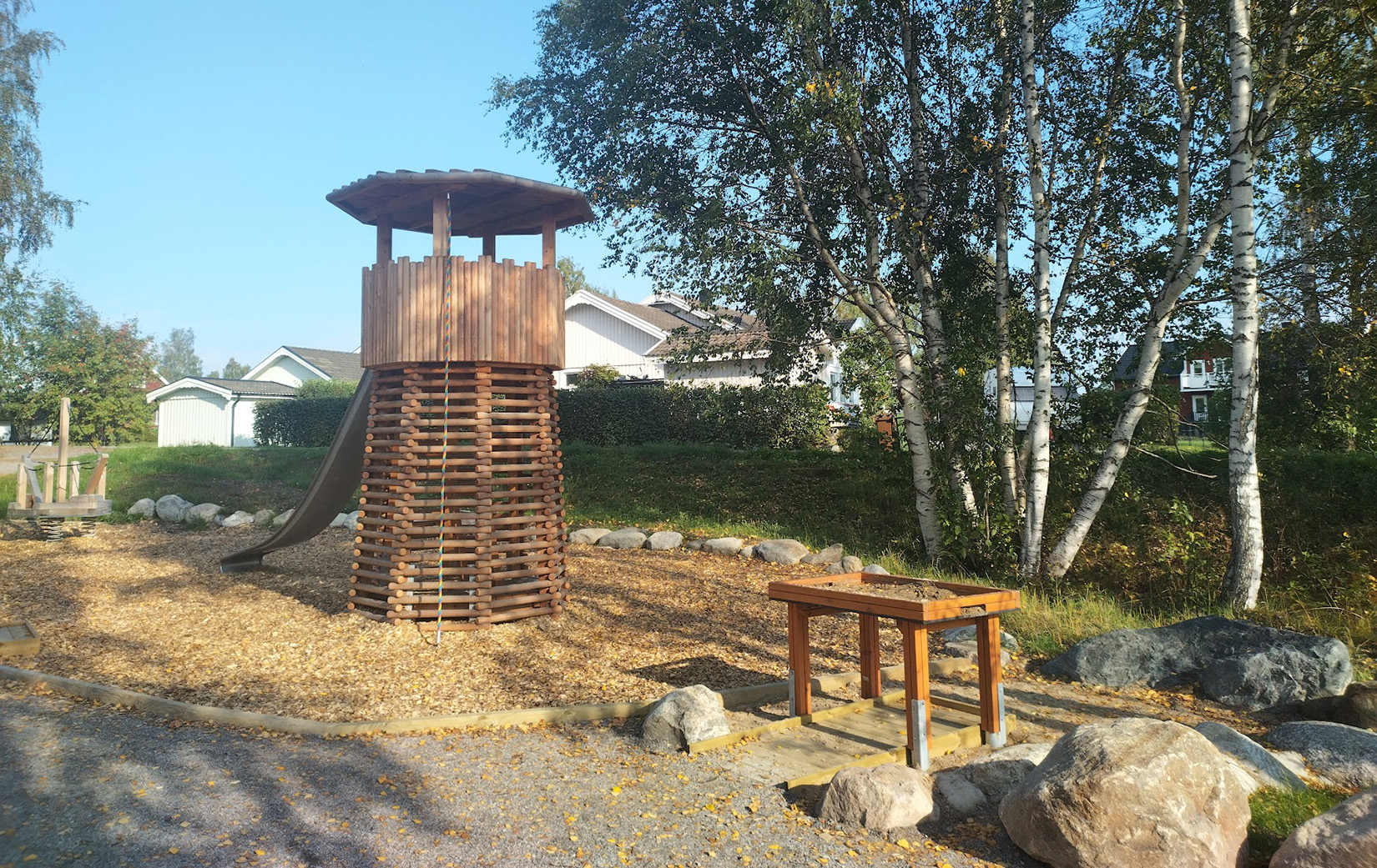 Ett klättertorn i naturfärgat trä med rutschkana