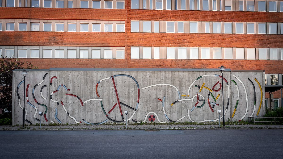 Vy över betongreliefen Hällristningar föreställande ett spädbarn.