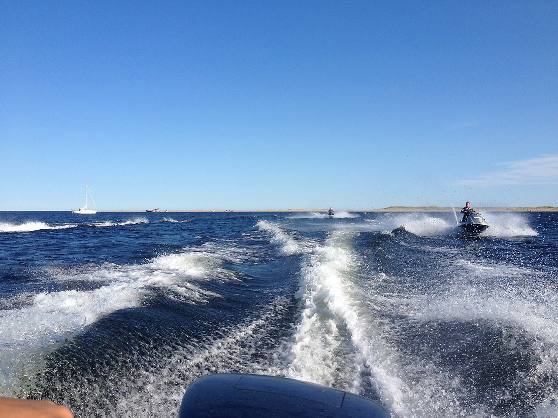 Svallvågor från båt med efterföljande vattenskotrar i Luleå skärgård