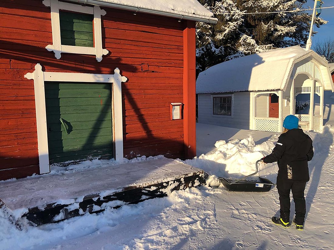 Person som skottar snö utanför en gammal byggnad på Hägnan i Luleå